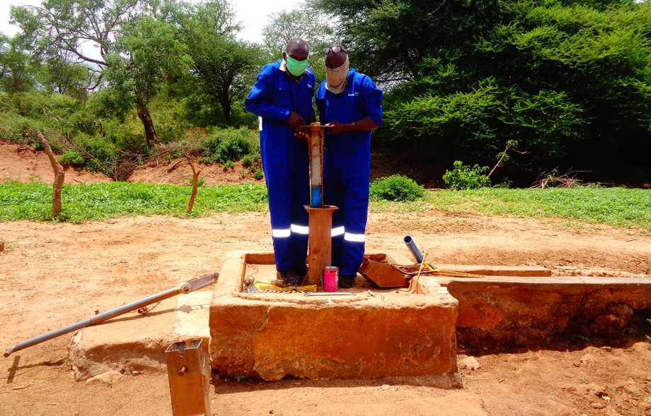 Fundifix mechanics wearing masks while fixing a handpump. Credit: Musenya Sammy